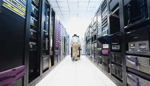 Man pushing cart down data center aisle.