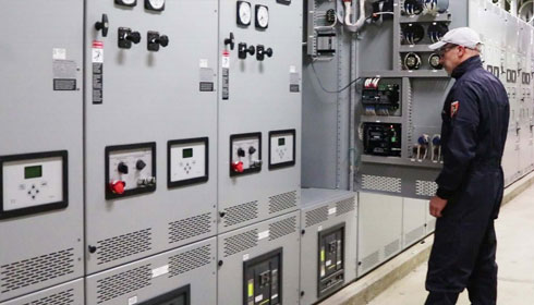 Engineer inspecting an ASCO 7000 series medium voltage paralleling switchgear