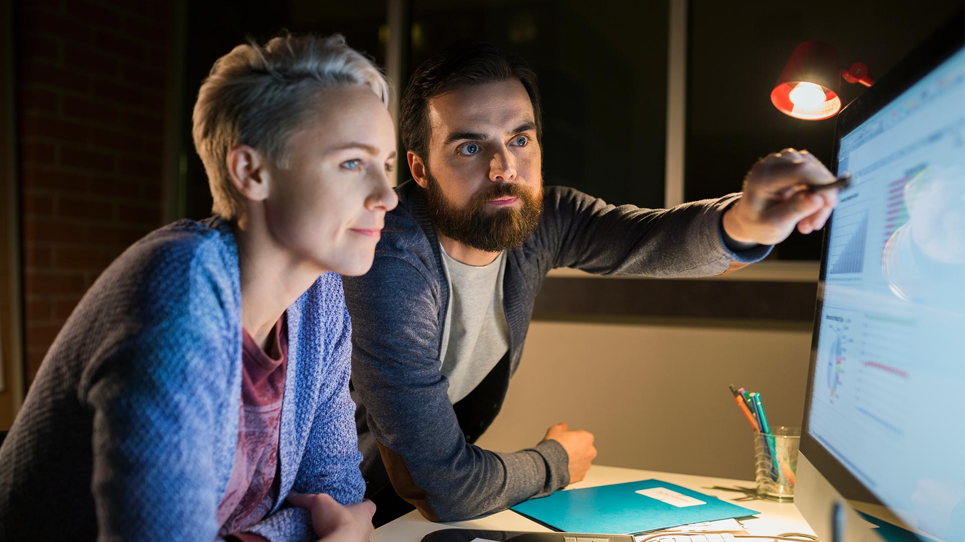 A man showing something on screen to his colleague