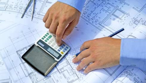 Hands with the tool on a background of project drawings