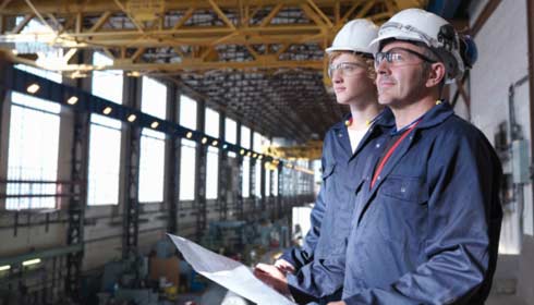 Two engineers using plans in a factory