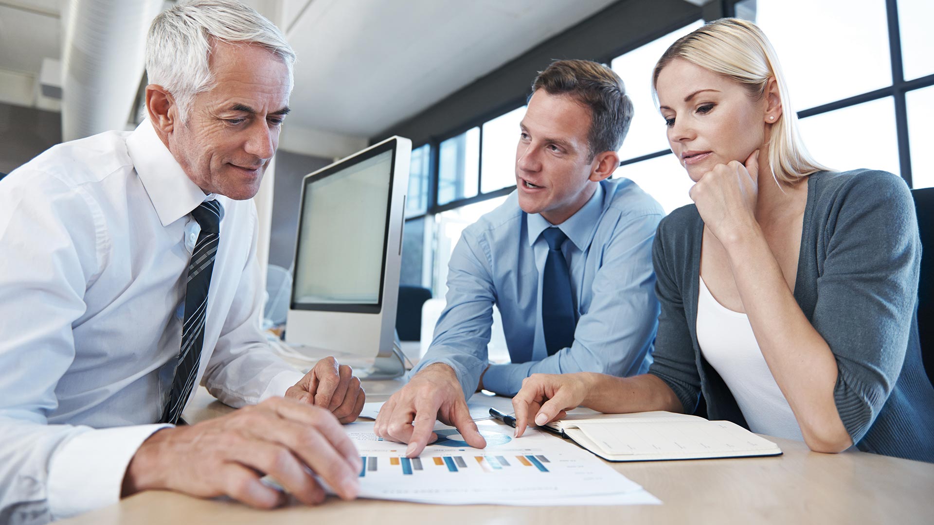 Three business people discussing test results next to a computer