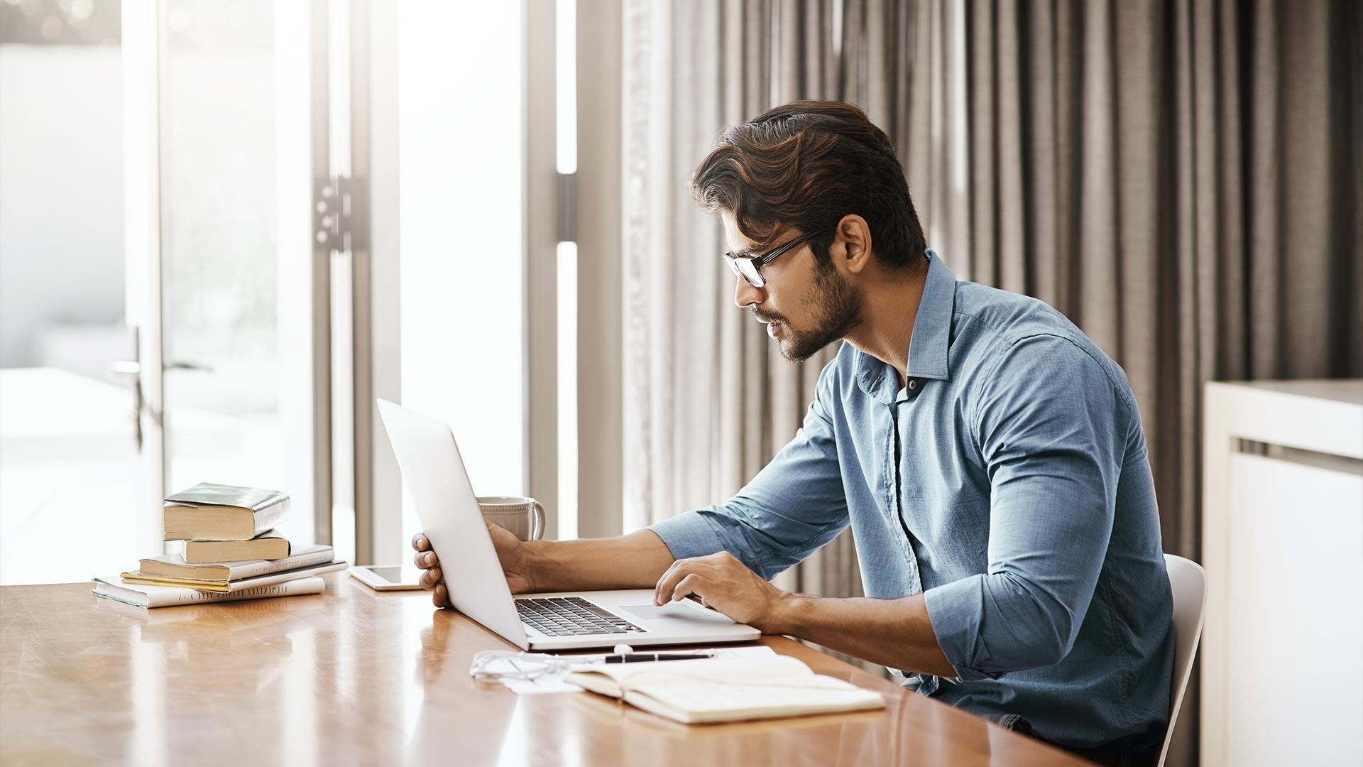 man sitting at his desk working on a laptop