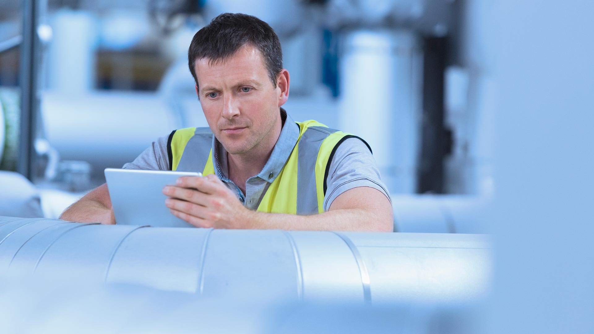 A worker holding a digital tablet in a factory