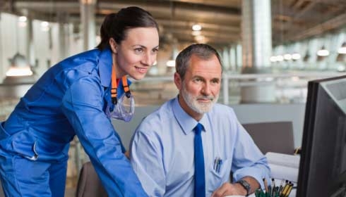 Businessman and engineer using computer in factory, facility management software, sustainability consulting.