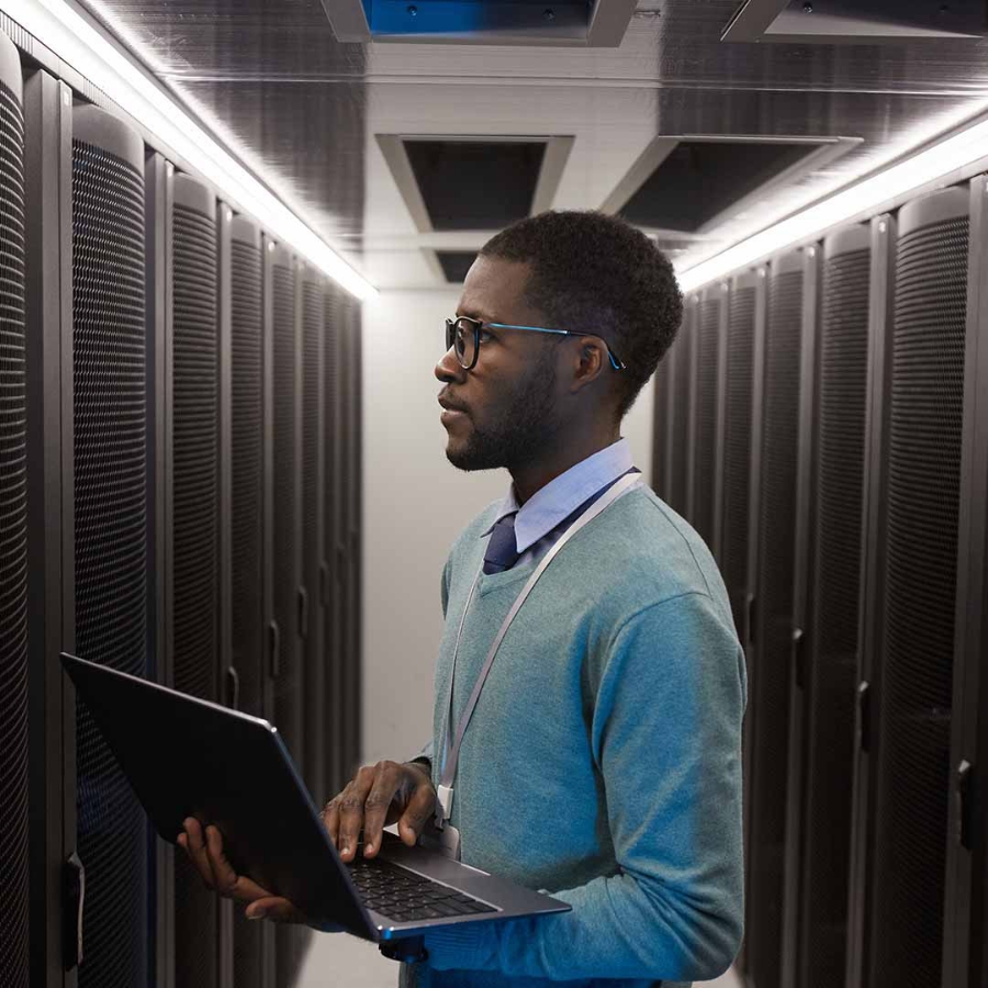 IT professional inside a server room with a laptop in his hand