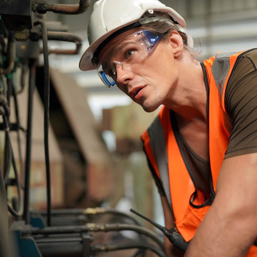 Closeup of a man wearing hard hat and working inside a factory