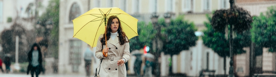 A young lady walking on street with umbrella while it is raining