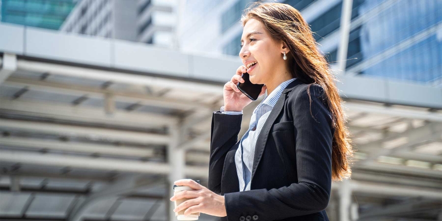 A business working talking on phone while holding a coffee cup in other hand