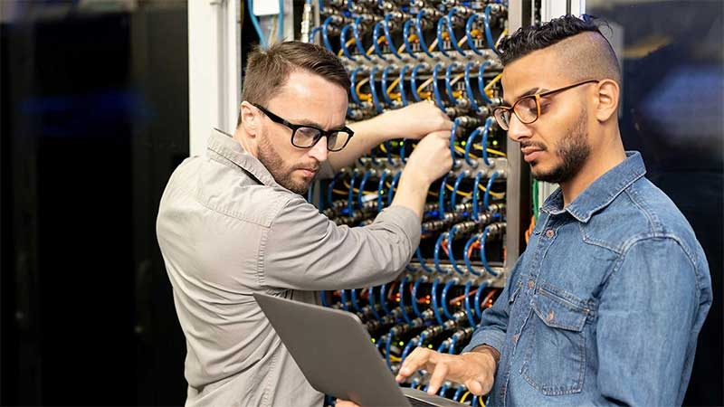 Two young IT professional checking a data server