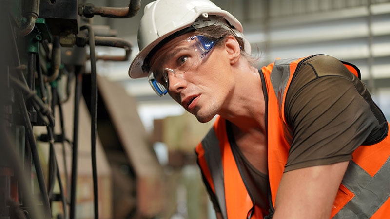 Closeup of a man wearing hard hat and working inside a factory