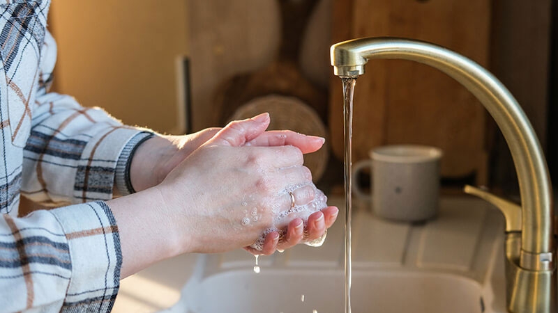 A person washing hands from a faucet