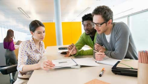 Three business colleagues discussing technical documents