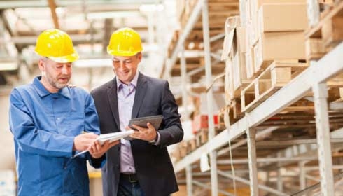 A project manager and site engineer discussing plans in a factory.