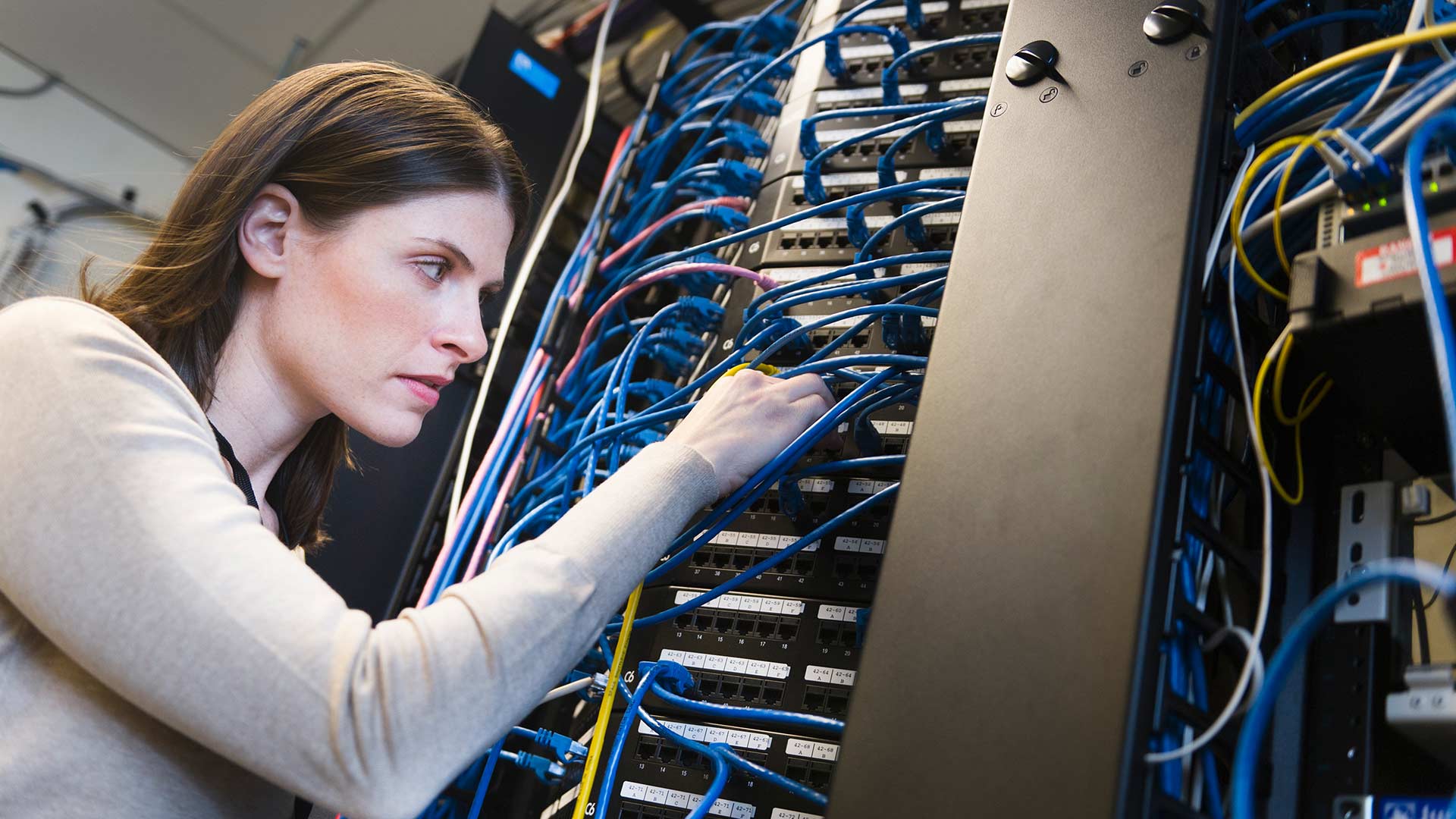 IT technician working on data center and looking at tablet, internet of things, energy management software, machine control.