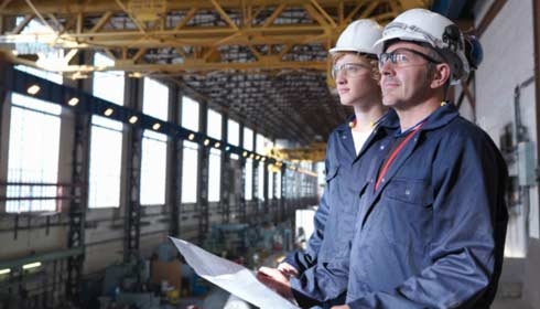 Two engineers using plans in a factory